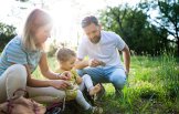 Eine Familie- Mann, Frau und Kind sitzen im Gras und spielen