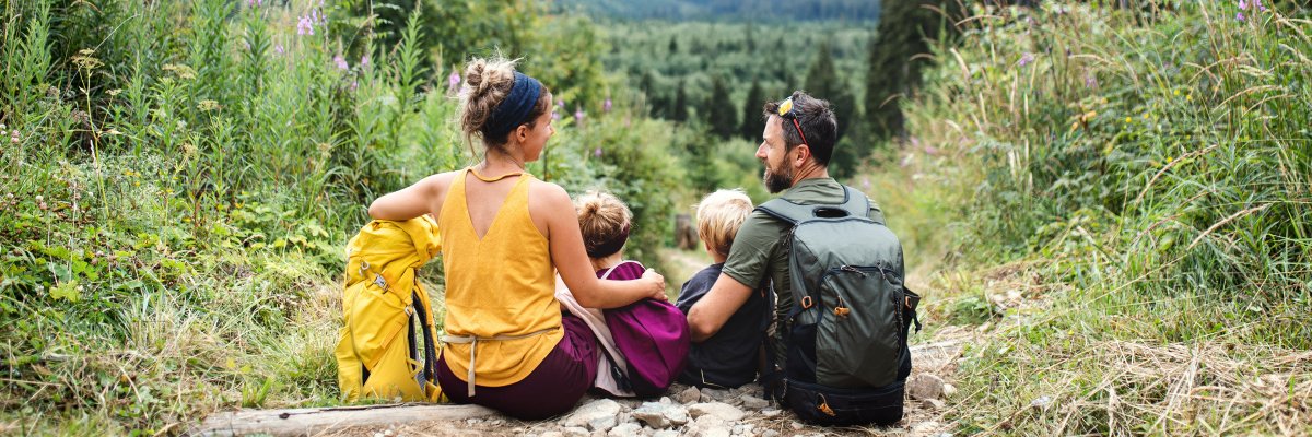 Eine Familie ( Vater, Mutter und Kind) beim Wandern. Sie sitzten auf einem Felsvorsprung
